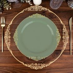 a green plate sitting on top of a wooden table next to silverware and flowers