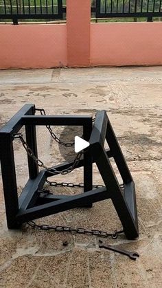 a black clock sitting on top of a stone floor next to a fence and gate