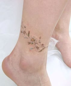 a woman's foot with a flower tattoo on her left ankle and the bottom part of her leg