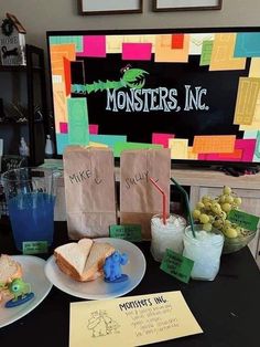 a table topped with sandwiches and drinks next to a sign that reads monsters, inc