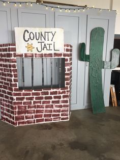 a fake brick jail cell with a green wooden door and sign that says county jail