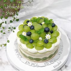 a cake decorated with grapes and daisies on a plate