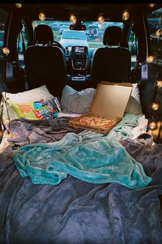 the back of a van with pizza and blankets on it's bed in the trunk