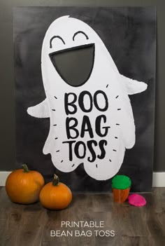 a black and white halloween bag with the words boo bag toss on it next to two pumpkins