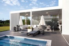 an outdoor pool with lounge chairs and umbrellas next to the side of a building