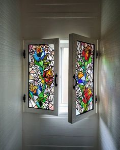 two stained glass windows in the corner of a room with white walls and flooring