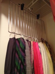 there are many scarves hanging on the rack in this closet, and one is not visible