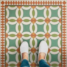 a person standing in front of a green and orange tile floor with circles on it