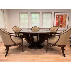 a dining room table with six chairs and a round glass top centerpiece in the middle