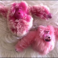 two pink stuffed animals laying on top of white fur