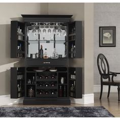 a black cabinet with wine glasses and bottles on it in a room next to a dining table