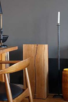 a wooden table topped with a lamp next to a black chair and a brown cabinet