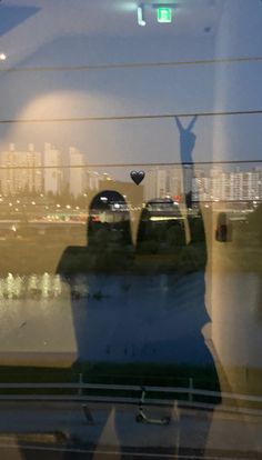 the reflection of a person standing in front of a window with their arms up and hands raised