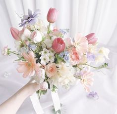 a bouquet of flowers is being held up by someone's hand on a white background