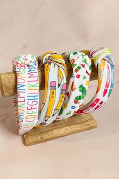 four bracelets are sitting on top of a wooden stand with the word hello kitty printed on them