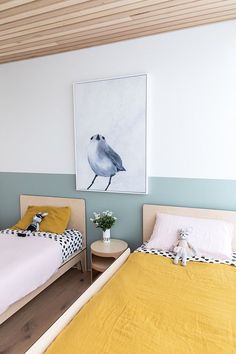 two beds in a bedroom with yellow and white bedding, one has a painting on the wall