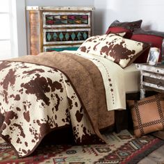 a bed with brown and white comforters on top of it next to a dresser