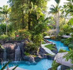 an outdoor swimming pool surrounded by trees and water features a waterfall that runs down to the ground