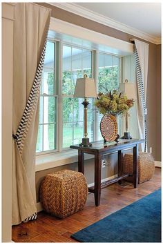 a living room filled with furniture next to a window covered in curtains and drapes