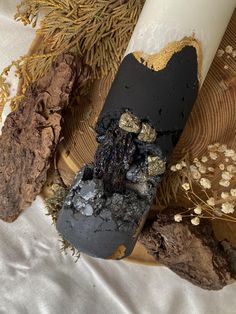 a candle and some rocks on a white cloth with gold flecks around it