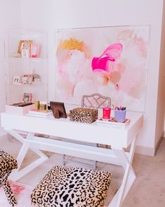 a white desk topped with a laptop computer sitting on top of a wooden chair next to a leopard print ottoman