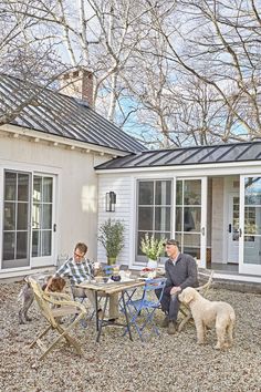 two men sitting at a table with their dogs