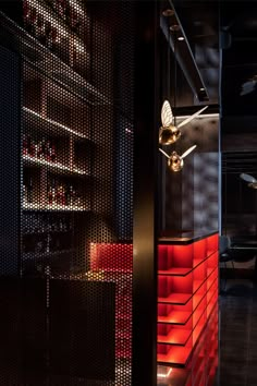 the interior of a restaurant with red and black lighting on the walls, along with wooden shelves