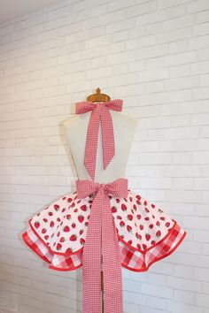 a red and white dress with polka dots on it, tied to a mannequin