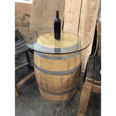 a wine bottle sitting on top of a wooden barrel next to a chair and table