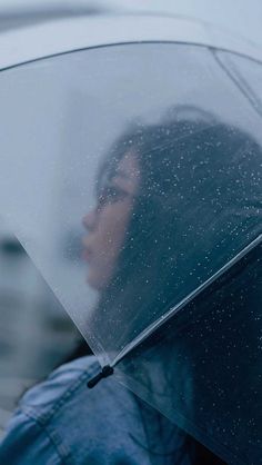 a woman holding an umbrella while standing in the rain with it's hood up