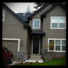 a car parked in front of a house with two garage doors and windows on each side