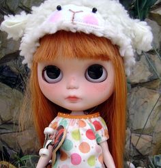 a close up of a doll with long hair and big eyes wearing a white hat