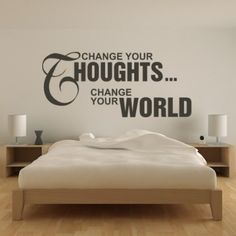 a bed sitting in a bedroom next to a wall with the words change your thoughts