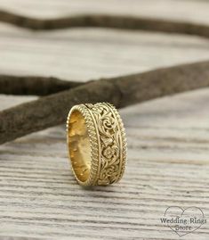 a gold wedding ring sitting on top of a wooden table