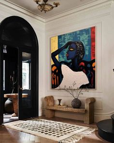 a large painting hangs on the wall above a bench in a room with wooden floors