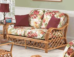 a living room with wicker furniture and red pillows on the couches in it