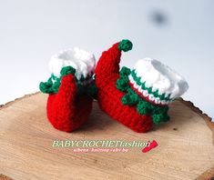 two crocheted baby booties sitting on top of a piece of wood