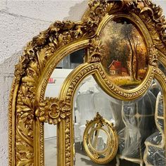 an ornate gold framed mirror with a painting on it