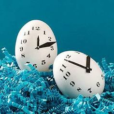 two clocks sitting on top of blue shredded paper