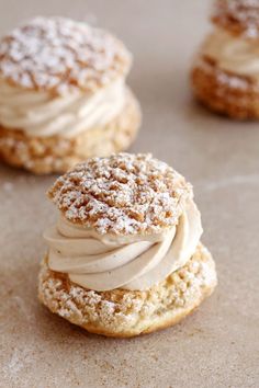 three cookies with icing and powdered sugar on top are sitting on a table