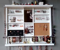 a white shelf filled with lots of different types of jewelry hanging on it's sides