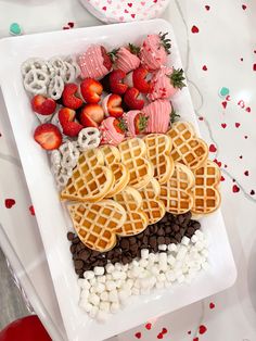 a white plate topped with waffles covered in chocolate and strawberries next to other food