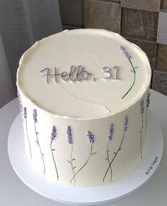 a white cake with lavender flowers and the word hello 31 on it is sitting on a plate