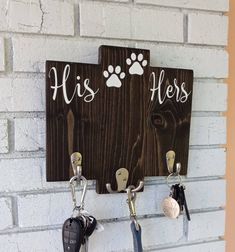 two key hooks hang on a brick wall with an image of a dog's head and paw prints