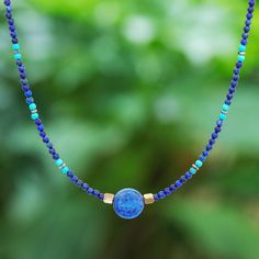 Thailand's Somluck Komolmith demonstrates her eye for fine detail and manual dexterity in this hand-beaded pendant necklace. A polished sphere of lapis lazuli commands your attention complemented by a beaded pattern featuring smaller lapis beads howlite beads and brass beads. On either side of the pendant golden hematite beads provide a visual anchor. The necklace features a spring ring clasp and extender chain of sterling silver. Blue Lapis Lazuli Round Necklace, Lapis Lazuli Necklaces With Natural Stones, Lapis Lazuli Natural Stones Round Necklace, Round Lapis Lazuli Necklace With Natural Stones, Sapphire Colored Lapis Lazuli Round Bead Jewelry, Sapphire-colored Lapis Lazuli Round Beaded Jewelry, Sapphire Lapis Lazuli Beaded Necklace, Lapis Lazuli Gemstone Beads Necklaces, Lapis Lazuli Round Beads Jewelry For Healing