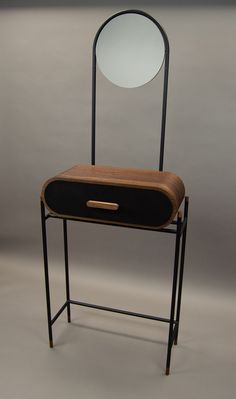 a mirror sitting on top of a wooden table next to a black and brown chair