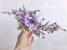 a hand holding a bouquet of purple flowers