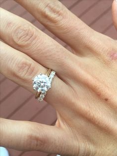 a woman's hand with a diamond ring on top of her finger and an engagement band