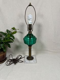 a green lamp sitting on top of a table next to a potted plant