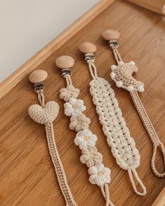 four crocheted hair clips with hearts and flowers on them sitting on a wooden surface